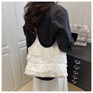 Rear view of model wearing a white lace tote bag with tiered ruffles and embroidery