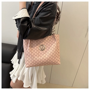Detail of pink tote bag with M-pattern print and chain strap shown on a model