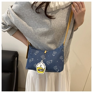 Detail of blue denim shoulder bag with white bear print and yellow leather strap