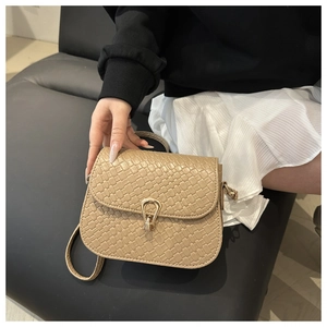 Detailed view of beige woven texture shoulder bag with gold horseshoe buckle and strap