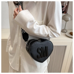 Detail of heart-shaped crossbody bag with bold SM letters and textured finish