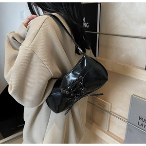Detail of black glossy patent leather underarm bag with side ribbon decorative tie