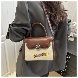 Detail of canvas and leather patchwork handbag with timeto embroidery and metal clasp