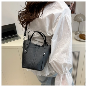 Detail of black pebbled leather bucket bag with silver studs and thin crossbody strap