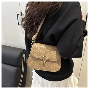Detail of woven texture small square bag with gold buckle on crossbody shoulder strap