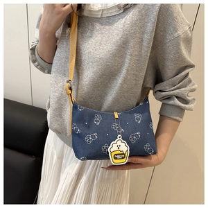 Detail of blue denim underarm bag with white bear print and yellow leather strap