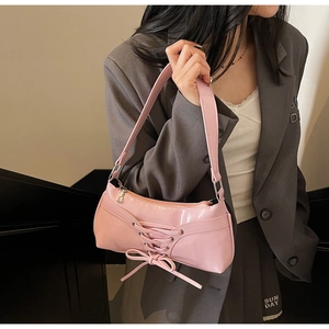 Pink glossy patent leather underarm bag with decorative lace-up bows and metallic zipper