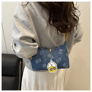 Close-up of printed denim underarm bag with white bear pattern and cake charm detail