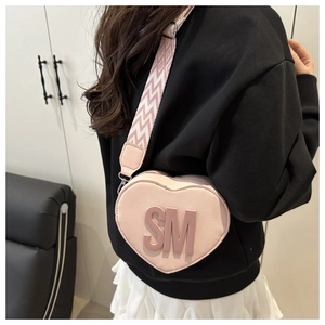 Close-up of pink heart-shaped bag with 3D letters and stylish patterned wide strap