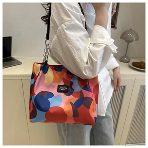 Detail of colorful geometric print nylon tote with leather logo and silver chain strap