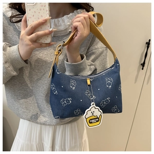 Detail of blue denim shoulder bag featuring white bear print and yellow leather strap