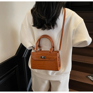 Rear view of a model carrying the brown crocodile embossed Kelly style handbag on stairs