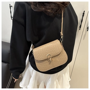 Detail view of beige crossbody bag with faux crocodile texture and gold teardrop lock