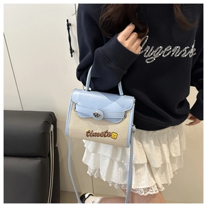 Detail view of woven light blue and beige crossbody bag with timeto logo and floral pattern