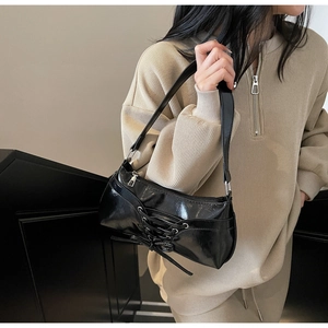 Chic black patent leather underarm bag with vintage lacing detail shown on a model