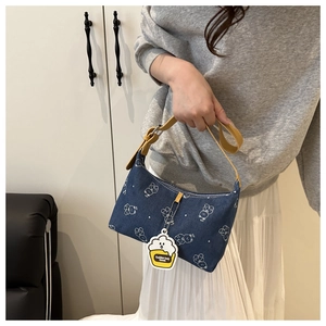 Detail of blue denim shoulder bag with white bear print and yellow cheese charm accessory