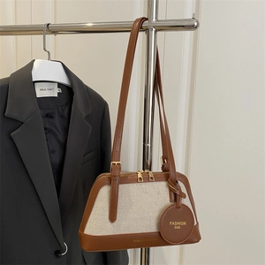 Chic shell-shaped canvas and brown leather crossbody bag hanging on a suit
