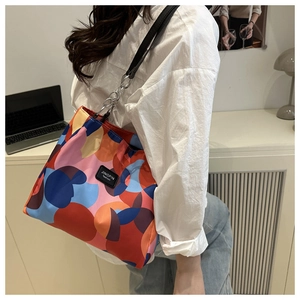 Detail of color-block patterned tote bag worn by a model in a modern office setting