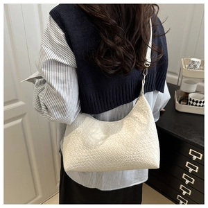 Close-up of a stylish white woven PU underarm bag carried by a model in commuter outfit