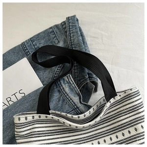 Détail d'un sac cabas tissé noir et blanc avec des motifs géométriques et de larges anses