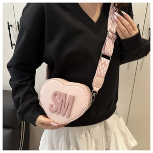 Detail of pink heart-shaped bag with embossed SM letters and wide geometric strap