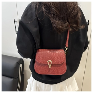 Detailed view of dark red woven texture saddle bag with golden horseshoe buckle on a model