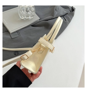Détail du sac bandoulière crème montrant la structure trapèze et les boucles dorées