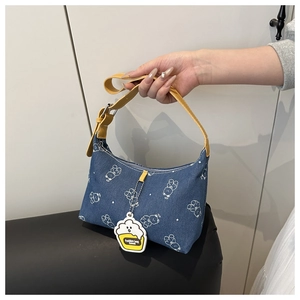 Detail of blue denim underarm bag with white bear prints and yellow leather strap