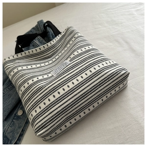 Détail d'un grand sac cabas tissé à rayures noires et blanches avec texture canevas et poignées