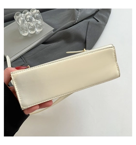 Gros plan d'un sac à main en cuir blanc crème avec coutures précises et finitions dorées