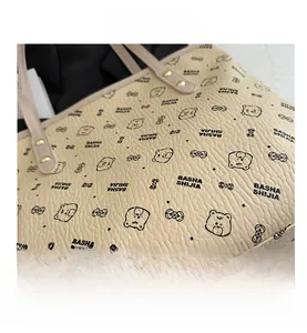 Detailed close-up of textured beige faux leather tote bag with elegant bear print