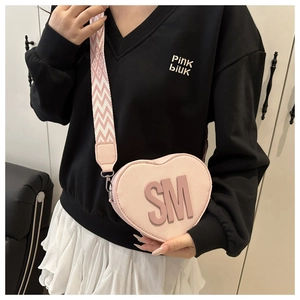 Close-up of pink heart-shaped crossbody bag with SM 3D letters and woven wide strap