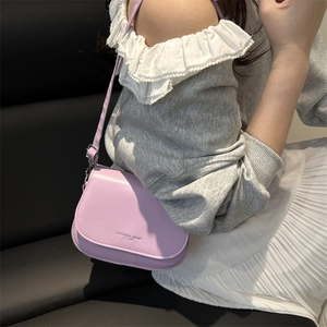 Sacoche selle en cuir violet clair avec bandoulière réglable portée par un mannequin
