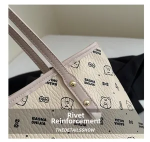 Close-up of golden rivet reinforcement and fine stitching on beige tote bag handle