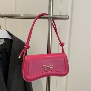 Rose pink faux leather crossbody bag with a gold metal bow clasp and knotted strap detail