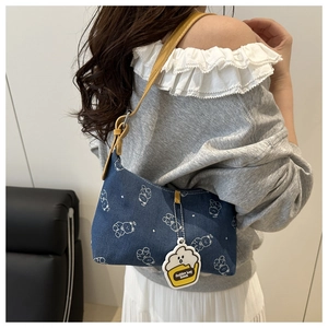 Close-up of blue denim shoulder bag with white bear print and yellow leather strap
