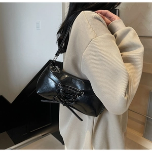 Close-up of black glossy PU underarm bag featuring decorative lace-up drawstring detail
