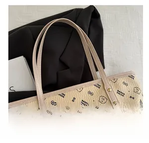 Detail of lychee pattern leather tote bag with bear print and sturdy gold rivet handles