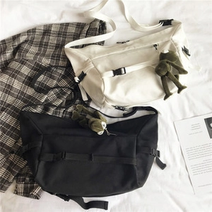 Detail of canvas tote bags with adjustable buckle straps and plush frog pendants