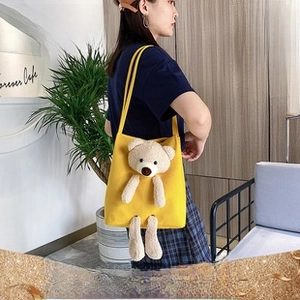Detail of yellow canvas tote bag featuring a 3D plush bear and sturdy shoulder straps