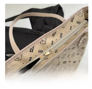 Close-up of smooth gold metal zipper and litchi grain leather on beige tote bag