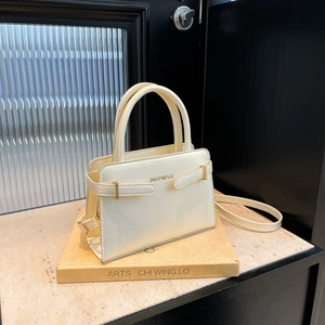 Sac à main chic beige brillant avec poignée et bandoulière réglable sur un support élégant