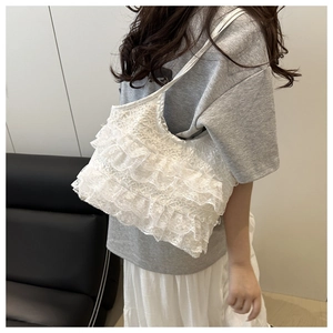 Close-up of white layered lace handbag showing intricate ruffles and soft tote design