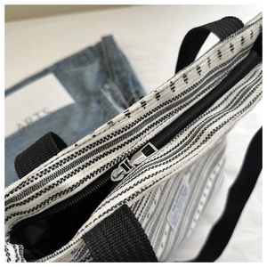 Détail du sac cabas tissé à rayures noires et blanches avec fermeture à glissière