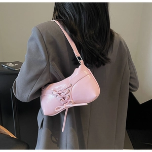 Close-up of a pink leather underarm bag with stylish lace-up design and matching strap