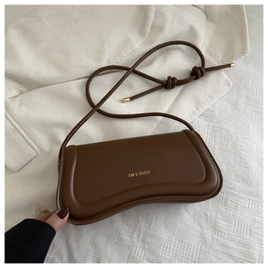 Detail view of brown leather bag with golden XM & BAGS logo and knotted strap detail