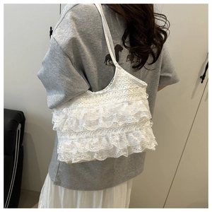 Macro shot of white multi-layer lace ruffles and intricate crochet texture on the tote bag