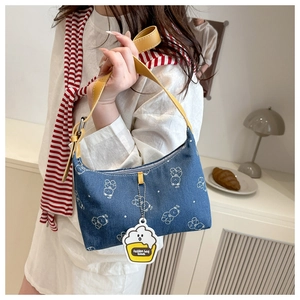 Detail of blue denim underarm bag with white bear print and yellow leather shoulder strap