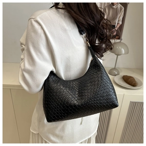 Back view of a model carrying a black woven leather armpit bag in a lifestyle setting