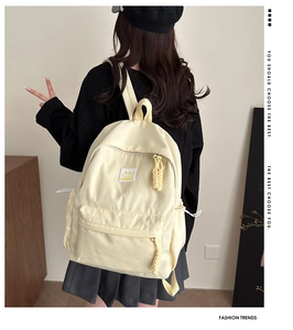 Side view of cream canvas backpack featuring yellow smiley patch and adjustable drawstring
